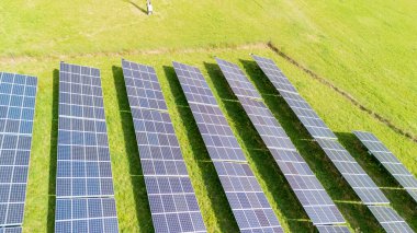 Yeşil alana yerleştirilmiş güneş panellerinin havadan görüntüsü. Güneş enerjisi sistemi, güneşten yenilenebilir enerji elde etmek için etkin bir şekilde çalışır..