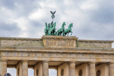 Brandenburg Kapısı ikonik bir Berlin simgesi bulutlu bir gökyüzünün altında ihtişamını gözler önüne seriyor. Tepedeki Quadriga heykeli Almanya tarihindeki zafer ve barışı simgeliyor..