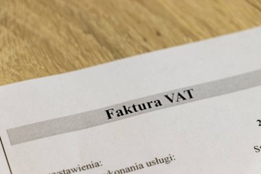 Hizmet tanımı ve vergi ayrıntıları gibi bir faturanın temel bileşenlerini gösteren ahşap bir yüzey üzerindeki KDV faturasının ayrıntılı yakın çekimi.