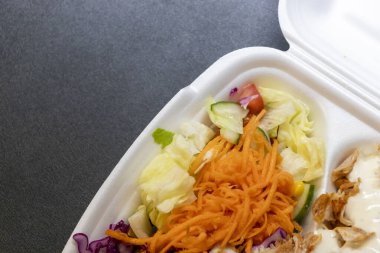 Taze ve renkli bir salata. İçinde kıyılmış havuç, marul ve salatalık var. Koyu bir yüzeyde servis ediliyor. Sağlıklı beslenme konsepti için ideal..