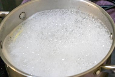 Kaynar su ve baloncuklarla dolu bir tencere dinamik bir mutfak sahnesi yaratıyor. Kaynama sürecini gösteren aşçılık teması ya da yemek pişirme dersleri için ideal.