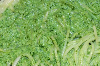 Canlı yeşil pesto sosuyla karıştırılmış spagetti yakın plan görüntüsü iştah açıcı ve taze bir yemek sunumu ya da tarif blogları için mükemmel..