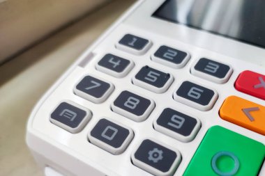Modern bir perakende ortamında sayısal tuşlara ve kontrol fonksiyonlarına sahip dijital ödeme terminaline yakın plan. Finansla ilgili görseller için ideal.