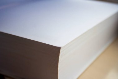 Ofis sanatı veya eğitim ortamları için doğal ışıklandırma için ideal düz kenarlı kalın beyaz kağıt yığınının yakın plan görüntüsü.