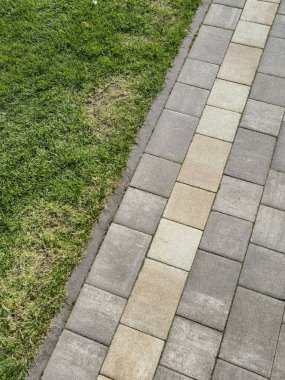 Yeşil çimen ve toprak parçasının yanında iyi korunmuş tuğla bir yolun yakın görüntüsü. Peyzaj ve açık hava tasarım temaları için ideal.