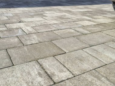 Güneşli bir yolda dokulu kaldırım taşlarının yakın görüntüsü geometrik desenler ve yıpranmış yüzeyler peyzaj veya kentsel tasarım projeleri için idealdir..