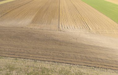 Farklı şekillerde tarımsal alanların havadan görünüşü. Manzara, tarım uygulamalarını ve mevsimsel değişiklikleri yansıtan toprak dokusu ve renklerini çeşitlendiriyor..