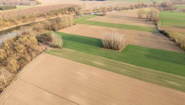 Tarım arazilerinin havadan görünüşü ve verimli toprakların yeşil çimenler ve kahverengi topraklarla ayrılmış bölümlere bölündüğü huzurlu bir nehir..