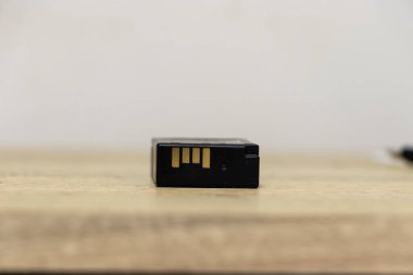 Ahşap bir yüzeye yerleştirilmiş, bağlantılarını ve yapısını vurgulayan siyah bir kamera bataryasının yakın çekim görüntüsü. Fotoğraf ekipmanları için gerekli.