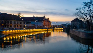 Wroclaw Polonya 'nın güzel şehir manzarası günbatımında tarihi binaları ve alacakaranlık altında sakin nehir yansımalarını vurguluyor.