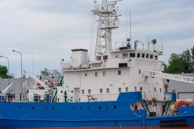 Gdansk Polonya - 18 Haziran 2022: ZODIAK adlı büyük mavi-beyaz bir araştırma gemisi yeşil ve kentsel manzarayla çevrili limana yanaştı.