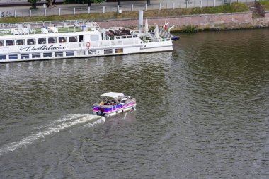 Wroclaw Polonya - 16 Haziran 2022: Küçük bir tur teknesi Odra Nehri 'nde daha büyük bir yolcu gemisinin yanında seyrediyor..