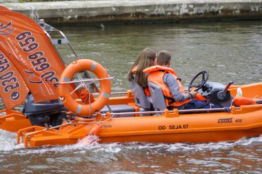 Wroclaw Polonya - 16 Haziran 2022: Genç bir çift canlı turuncu bir teknede can yelekleriyle nehirde romantik bir tekne gezintisi yapıyor..