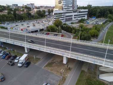 Rzeszow Polonya - 3 Haziran 2024: Modern binaların inşaat sahaları ve kentsel kalkınmanın sergilendiği yeşil alanlarla dolu işlek bir şehir yolunun havadan görünüşü.