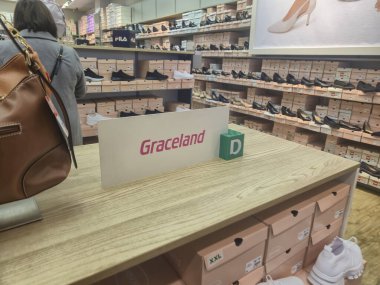 Przemysl Polonya - Mart 12025: Bir ayakkabı mağazasında bir müşteri ayakkabı seçeneklerine bakarken Graceland tabelası ekranın hemen üstünde duruyor.