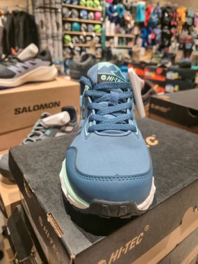 Przemysl Poland - Mart 12025: Arka planda çeşitli ayakkabı markalarıyla çevrili canlı bir spor mağazasında HI-TEC 'ten mavi bir spor ayakkabısının yakın çekimi.