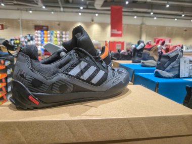 Przemysl Polonya - Mart 12025: Dağcılar için gelişmiş tasarım ve işlevsellik sergileyen bir spor perakende mağazasında sergilenen parlak siyah bir tırmanma ayakkabısının yakın çekimi.