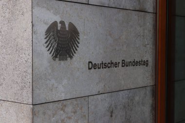 Berlin Almanya - 11 Nisan 2025: Deutsche Bundestag 'ın yakın çekimi Alman armasını siyaseti ve demokrasiyi sembolize eden dokulu taş bir duvarda gösteriyor.