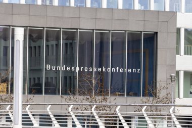 Berlin Almanya - 11 Nisan 2025: Geniş cam pencereli modern ofis binası 'Bundespressekonferenz' yazısını sergiliyor.