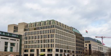 Berlin Almanya - 11 Nisan 2025: Modern mimari binalar şehir manzarasında bulutlu bir gökyüzüne karşı karmaşık tasarım detayları sergiliyor.