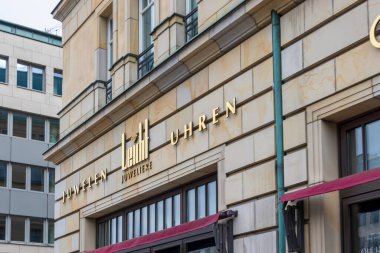 Berlin Almanya - 11 Nisan 2025: Altın tabelalı bir mücevher ve saat dükkanının şık vitrini. Büyüleyici mimari detaylar şehir atmosferini geliştirir.