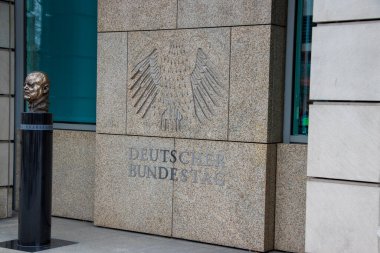 Berlin Almanya - 11 Nisan 2025: Alman siyasi mirasını ön plana çıkaran bir kartal amblemi ve bronz büstün yer aldığı Deutscher Bundestag taş duvarının yakın çekimi.
