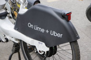 Berlin Almanya - 11 Nisan 2025: Sokağa park edilmiş Uber markalı bir Lime elektrikli bisikletin yakın çekimi. Bisiklet, modern kentsel ulaşım çözümleri ve sürdürülebilirliği temsil etmektedir..