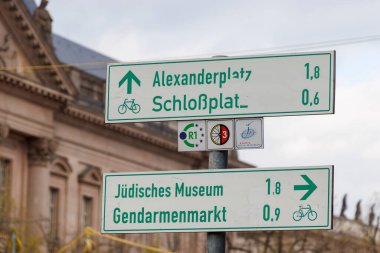 Berlin Almanya - 11 Nisan 2025: İskenderplatz ve Yahudi Müzesi 'ni gösteren yön işaretleri canlı bir kültür ortamında şehir navigasyon ve şehir mimarisini gösteriyor.