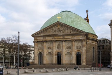 Berlin Almanya - 11 Nisan 2025: Berlin Katedrali, modern mimari ve bulutlu gökyüzü ile çevrili yeşil bir kubbeye ve karmaşık oymalara sahiptir..