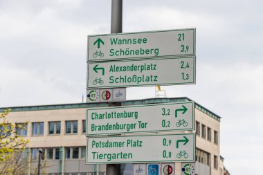 Berlin Almanya - 11 Nisan 2025: Charlottenburg Brandenburg Tor ve Potsdamer Platz gibi şehir simgelerine doğru popüler bisiklet rotalarını gösteren yön işaretleri.