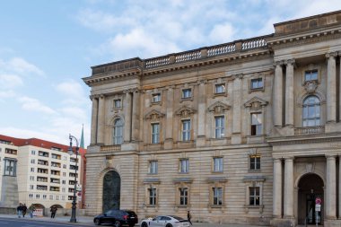 Berlin Almanya - 11 Nisan 2025: Gökyüzüne karşı dekore edilmiş büyük bir binanın tarihi mimarisi. Bölge yayalar ve araçlarla dolu..