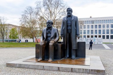 Berlin Almanya - 11 Nisan 2025: Karl Marx ve Friedrich Engels 'in bronz heykelleri, felsefe ve siyaset üzerindeki etkilerini simgeleyen bir parkta oturuyorlardı..