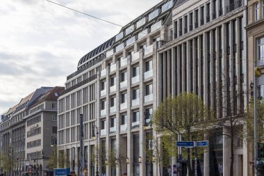 Berlin Almanya - 11 Nisan 2025: Modern mimari binalar bulutlu bir gökyüzüne karşı çağdaş ve geleneksel tasarımların bir karışımını sergileyerek şehir caddesini oluşturdu.