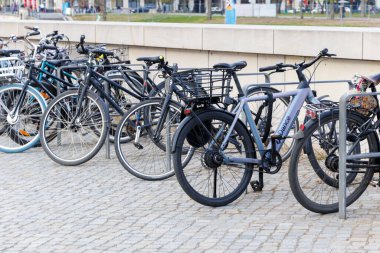 Berlin Almanya - 11 Nisan 2025: Açık bir gökyüzü altında çevre dostu taşımayı destekleyen çeşitli stil ve renklerin sergilendiği halka açık bir alanda park edilmiş bisiklet koleksiyonu.