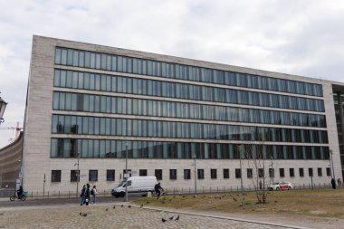 Berlin Almanya - 11 Nisan 2025: Şehir merkezinde camdan pencereleri olan modern bina. Şehir yaşamını ve çağdaş mimariyi sergileyen insanlar.