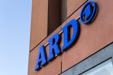 Berlin Almanya - 11 Nisan 2025: Alman medya kimliği ve kültürünü sembolize eden açık mavi gökyüzüne karşı modern bir binanın ön cephesinde belirgin ARD logosu.