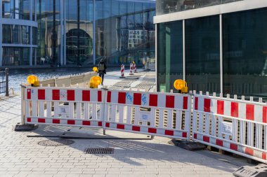 Berlin Almanya - 11 Nisan 2025: Şehirdeki kentsel kalkınma ve altyapı değişikliklerini vurgulayan bir kanal yakınındaki inşaat engelleri erişimi engelliyor.