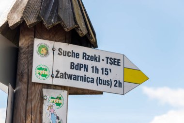 Bieszczady Ulusal Parkı 'ndaki yürüyüş güzergahları için, Sucha Rzeka ve Zatwarnica' ya giden yolları gösteren bir işaret direği. Parlak mavi gökyüzü dışarıdaki manzarayı güzelleştirir..