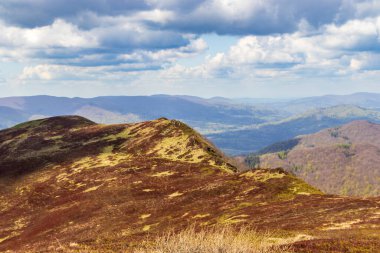 Bieszczady Dağları 'nın panoramik manzarası. Parça parça bulutlu gökyüzü altında yemyeşil tepeler ve vadiler sergileniyor. Açık hava ortamlarında doğa güzelliğini sergilemek için mükemmel..