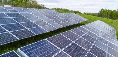 Güneş panelleri, yenilenebilir enerji için güneş ışığını yakalayan yeşil bir alana yerleştirildi. Açık gökyüzü ve doğal çevre sürdürülebilir teknolojiye odaklanmamızı sağlar..