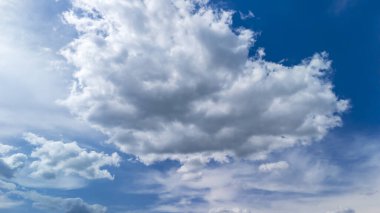 Pofuduk beyaz bulutlar parlak mavi bir gökyüzünde süzülür ve dingin bir atmosfer yaratır. Doğa geçmişi ya da açık hava koşulları için mükemmel..
