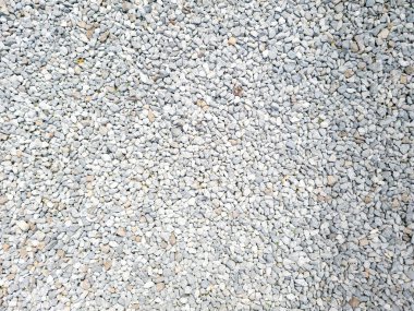 Peyzaj ve inşaat projeleri için ideal bir yüzeyi kaplayan küçük açık gri çakıl taşlarının yakın çekim görüntüsü. Doku doğal bir kırsal görünüm sunuyor..