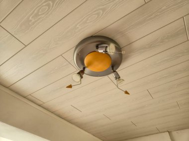 Ahşap aksanlı dairesel bir tasarımı ve modern iç mekanda aydınlatılabilen ayarlanabilir kolları olan şık tavan lambası..