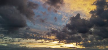 Dramatik günbatımı gökyüzü canlı bulutlar ve turuncu ve mavi renkler ile dolu. Alacakaranlık sırasında açık hava ortamları için çarpıcı bir doğal zemin oluşturuyor..