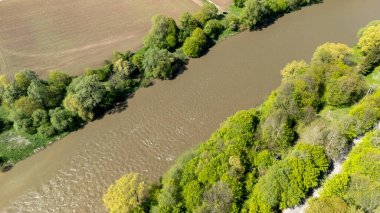 Bereketli yeşilliklerin arasından akan bir nehrin havadan görünüşü kahverengi su ve canlı bitki örtüsünün karışımı ilkbaharda doğanın güzelliğini gözler önüne seriyor..