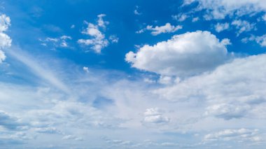 Beyaz kabarık bulutlarla dolu huzurlu mavi bir gökyüzü sakin bir atmosfer yaratır. Arka planlar için ideal doğa temalı projeler veya mevsimsel bağlamlar.