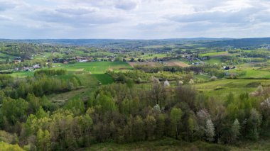 Parçalı bulutlu bir gökyüzünün altındaki yemyeşil tarlaların ve ormanların havadan görünüşü ilkbaharda doğa güzelliğini gözler önüne seriyor..