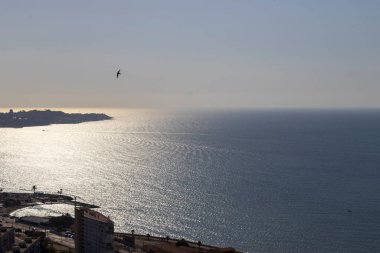 Gün doğumunda sakin Akdeniz 'e bakan sakin sahil şeridinin panoramik görüntüsü sabah ışığında parıldayan hafif dalgalarla sakin bir güzellik sergiliyor..