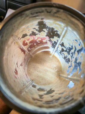 Boş bir blender kavanozunda kremalı dokular ve meyve parçacıkları içeren meyve suyu kalıntıları var. Gıda hazırlığı için ideal ve tazelik taşıyan mutfak ayarları.