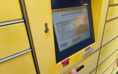 Lahde Almanya - 15 Nisan 2025: Posta servisinin bulunduğu yerde sevkiyat numaraları veya QR kodlarının taranması seçeneklerini gösteren modern bir parsel dolap ekranının yakın çekimi.